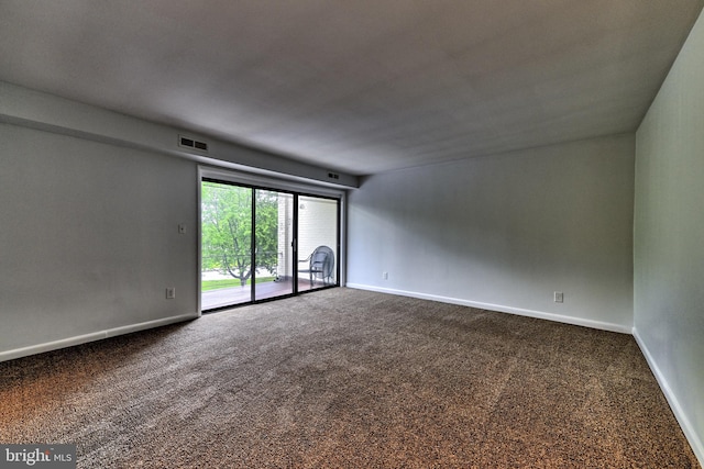 spare room with dark carpet and baseboards