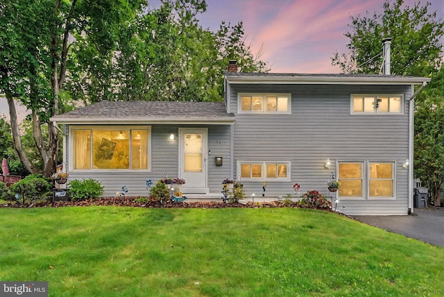 tri-level home with a chimney and a lawn