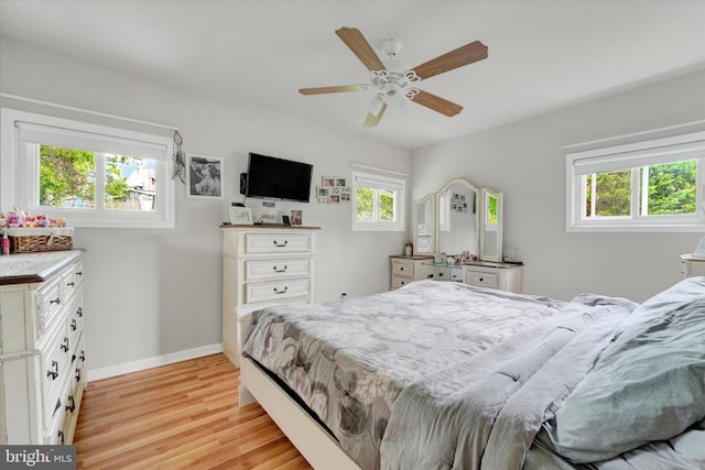 bedroom featuring multiple windows, light wood-style floors, baseboards, and ceiling fan