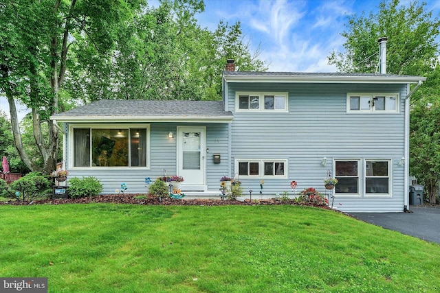 split level home with a chimney and a front lawn
