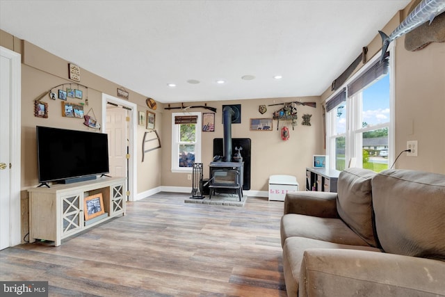 living area with a wood stove, healthy amount of natural light, wood finished floors, and recessed lighting