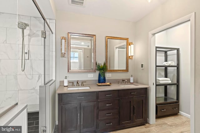 full bathroom featuring a tile shower and double vanity