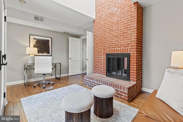 living area with wood finished floors, a fireplace, and baseboards