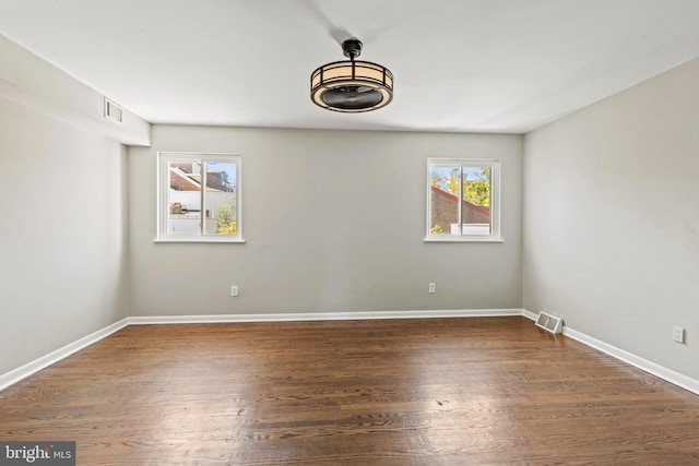 spare room with dark wood finished floors and baseboards