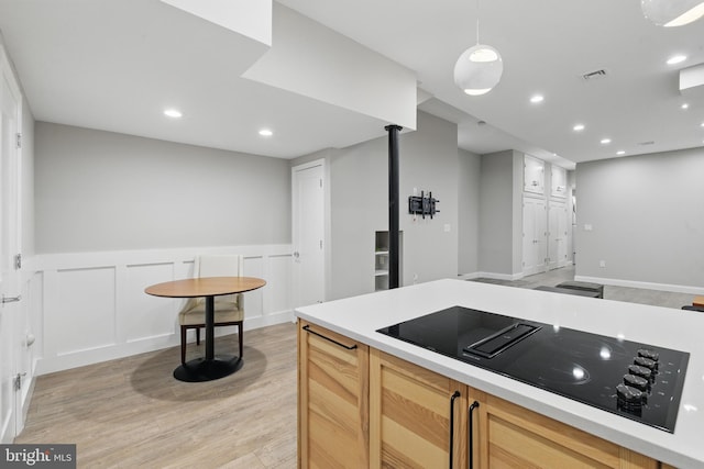 kitchen with black electric cooktop, light wood-type flooring, wainscoting, light countertops, and recessed lighting