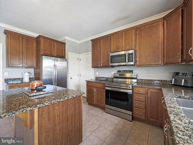67 Tinning Ct, Hedgesville, WV 25427 - kitchen with stainless steel appliances, dark stone countertops, light tile patterned floors, ornamental molding, and brown cabinetry