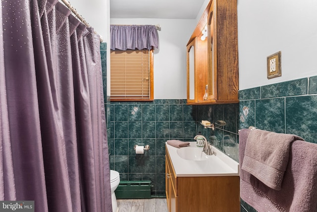 full bathroom with tile walls, toilet, vanity, a wainscoted wall, and curtained shower