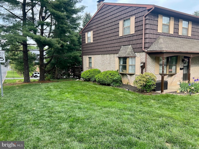 view of property exterior with brick siding, a yard, and a chimney