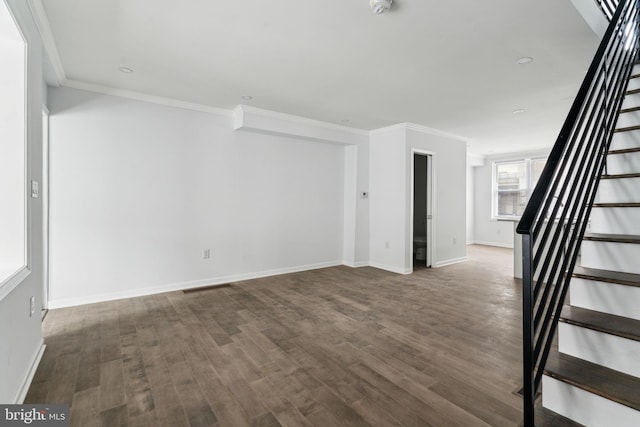 empty room with stairway, wood finished floors, baseboards, and ornamental molding