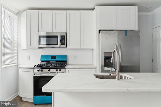 kitchen featuring appliances with stainless steel finishes, light stone counters, baseboards, white cabinets, and crown molding