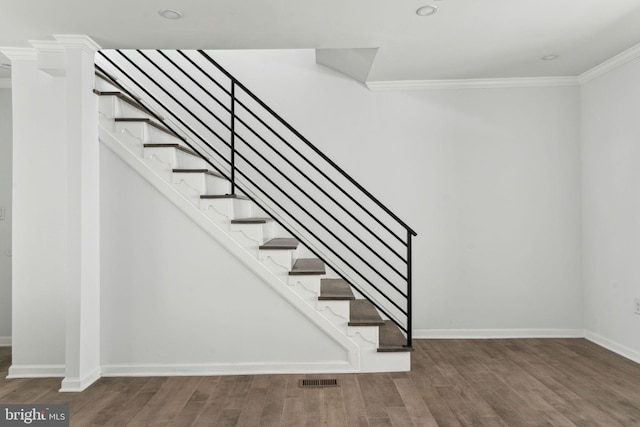 staircase with crown molding, wood finished floors, and baseboards