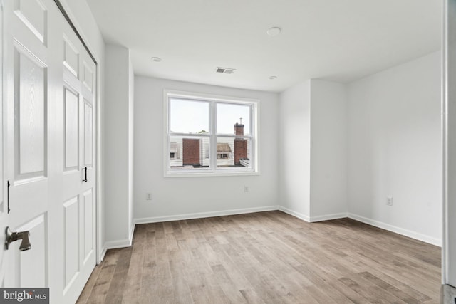 unfurnished bedroom with light wood-style flooring, baseboards, and a closet