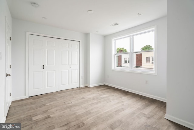 unfurnished bedroom with light wood finished floors, baseboards, and a closet