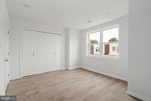 unfurnished bedroom with light wood-style floors, baseboards, and a closet