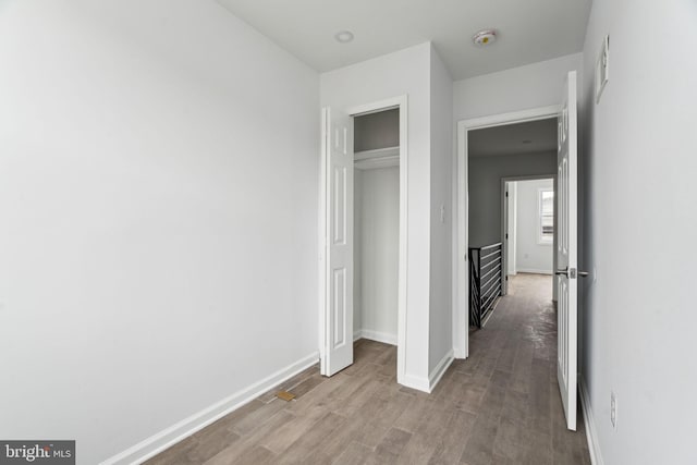 unfurnished bedroom with wood finished floors, baseboards, and a closet