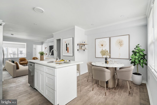 kitchen with a sink, ornamental molding, light wood-type flooring, dishwasher, and light countertops
