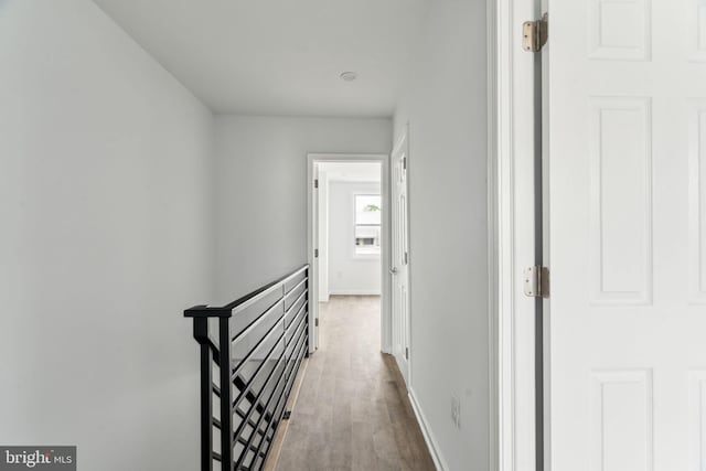corridor featuring an upstairs landing, wood finished floors, and baseboards