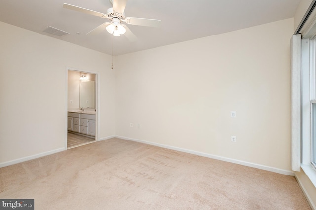 unfurnished bedroom with light colored carpet, baseboards, connected bathroom, and ceiling fan