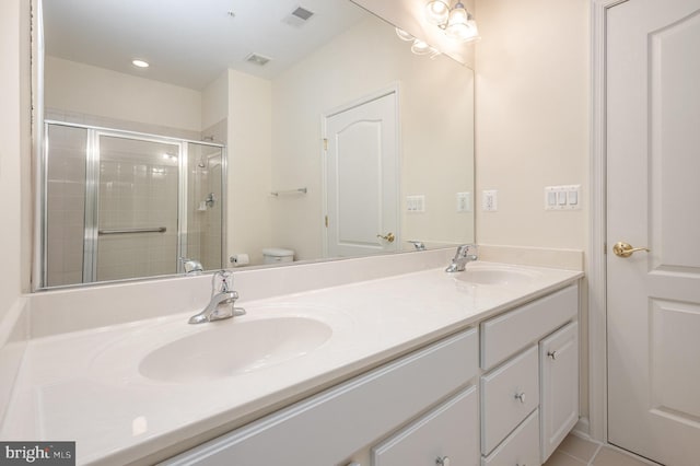 full bathroom featuring toilet, a stall shower, and double vanity