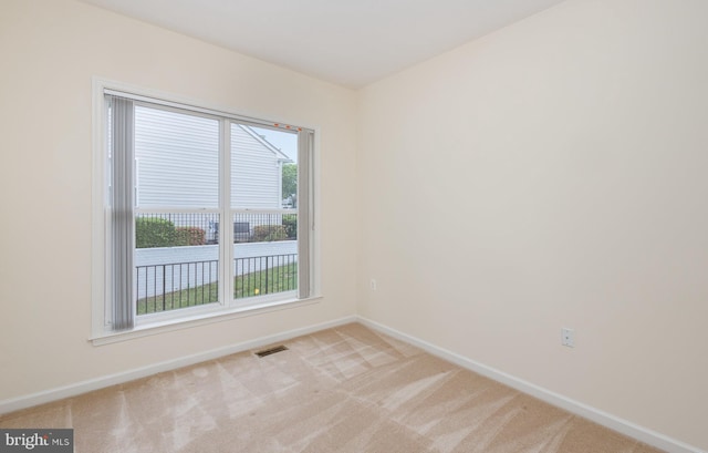 unfurnished room with baseboards, light colored carpet, and healthy amount of natural light