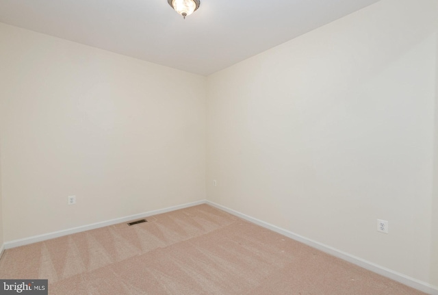 empty room featuring light carpet and baseboards