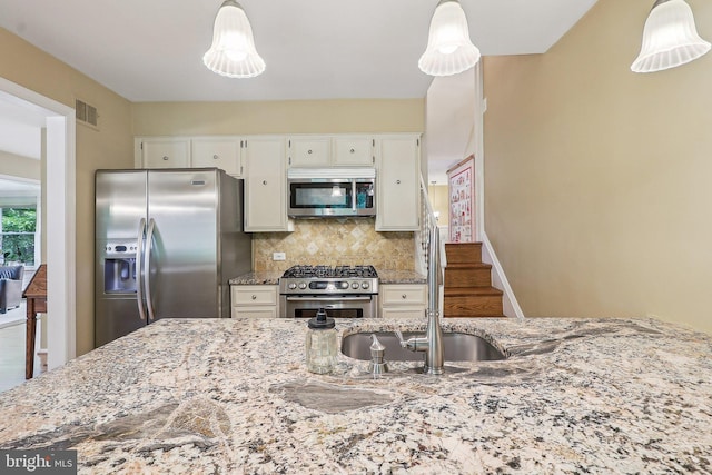 3919 30th St N, Arlington, VA 22207 - kitchen with stainless steel appliances, light stone countertops, tasteful backsplash, hanging light fixtures, and white cabinetry