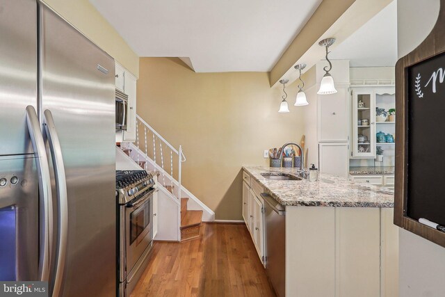 3919 30th St N, Arlington, VA 22207 - kitchen with stainless steel appliances, a sink, white cabinets, a peninsula, and light wood-style floors