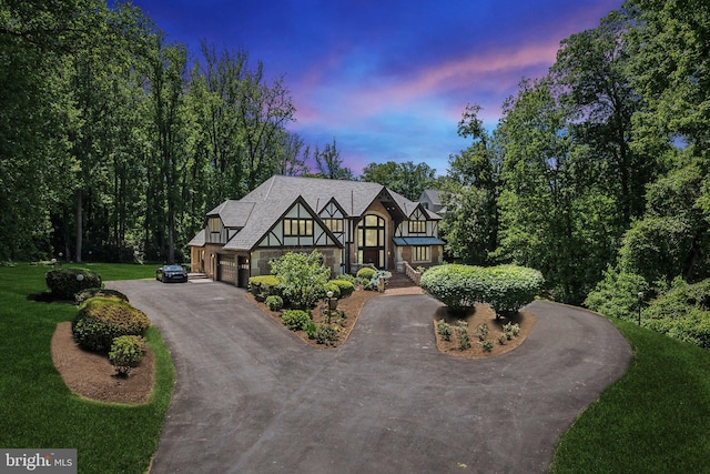 6723 Georgetown Pike, Mclean, VA 22101 - tudor-style house featuring curved driveway, stone siding, a garage, and a yard