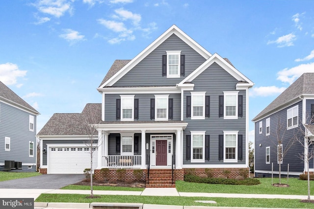 view of front facade with a porch, asphalt driveway, an attached garage, central AC unit, and a front yard