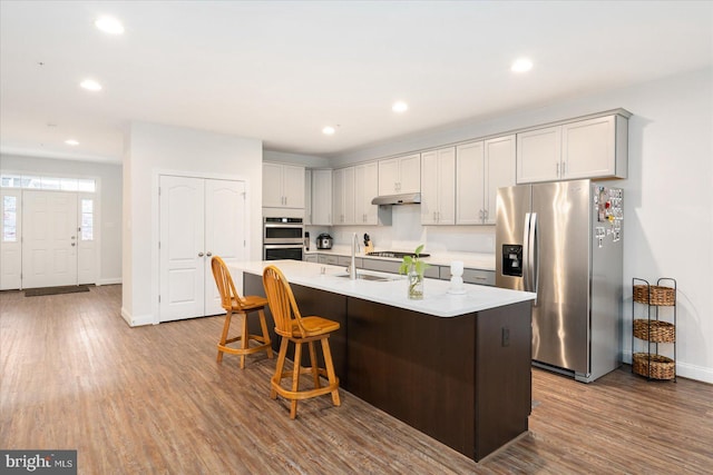 kitchen featuring appliances with stainless steel finishes, baseboards, wood finished floors, light countertops, and recessed lighting