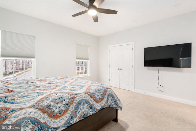 carpeted bedroom featuring multiple windows, baseboards, a closet, and a ceiling fan