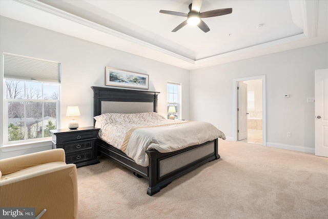 bedroom with light carpet, a tray ceiling, connected bathroom, and baseboards