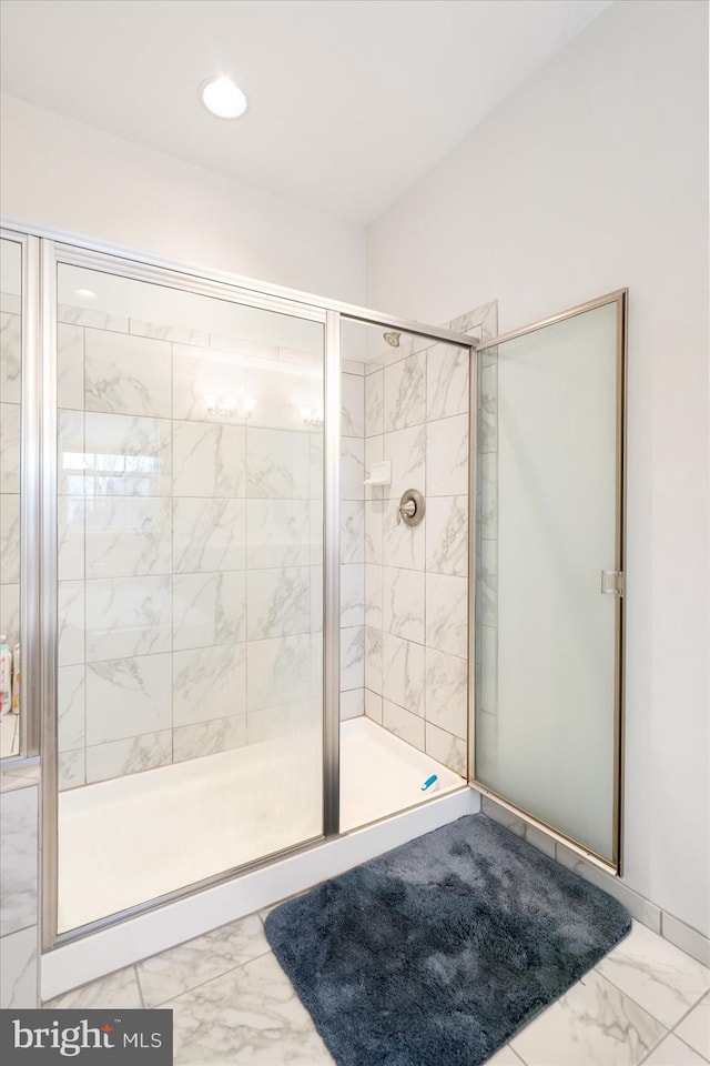 full bath with marble finish flooring and a shower stall