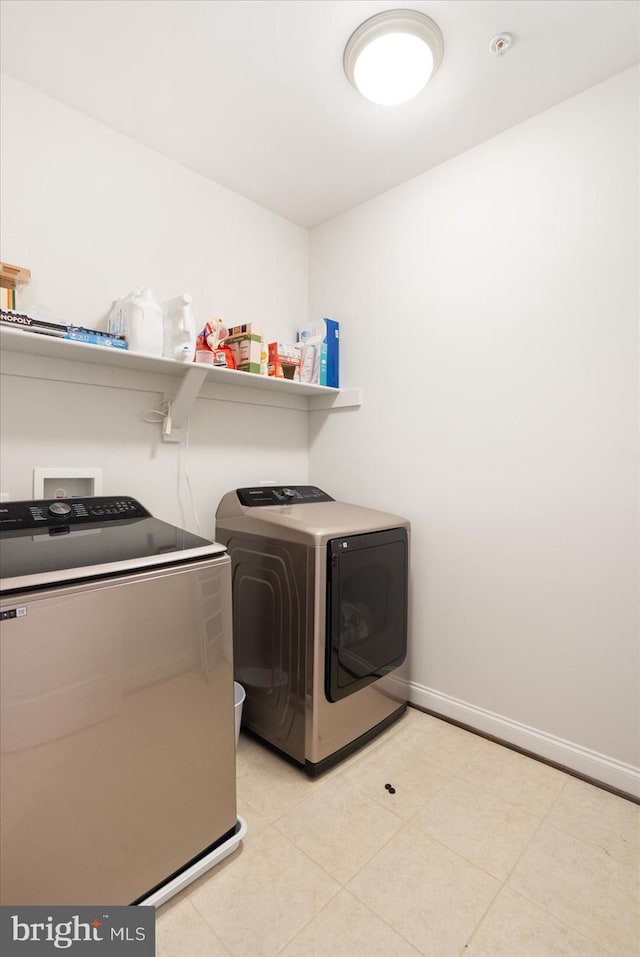 laundry area featuring washer and dryer, baseboards, and light tile patterned floors