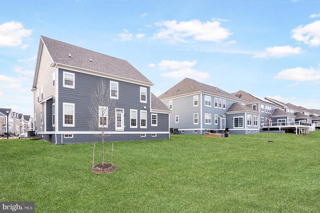 rear view of property with a lawn, a residential view, and central AC