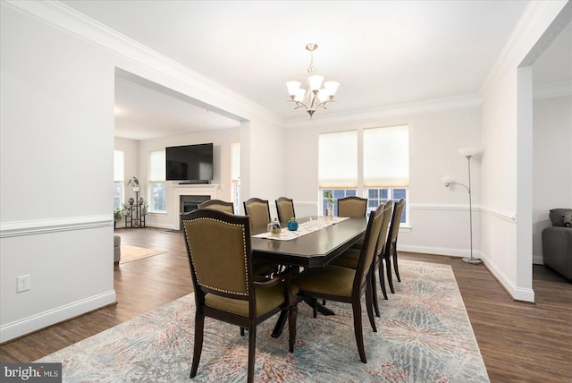 dining room featuring a chandelier, ornamental molding, baseboards, wood finished floors, and a fireplace