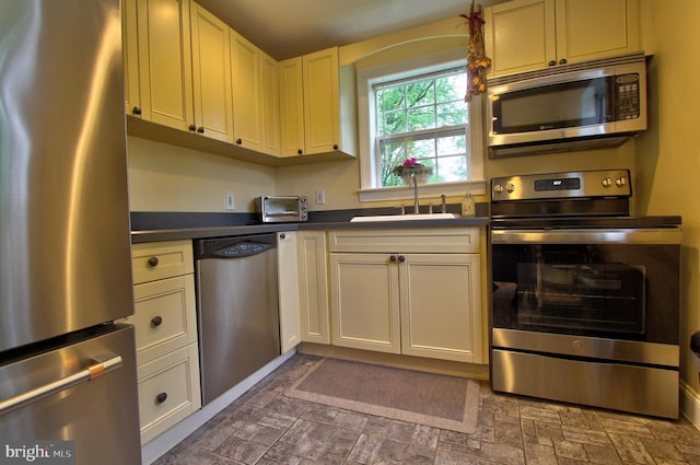 kitchen featuring appliances with stainless steel finishes, dark countertops, and a sink