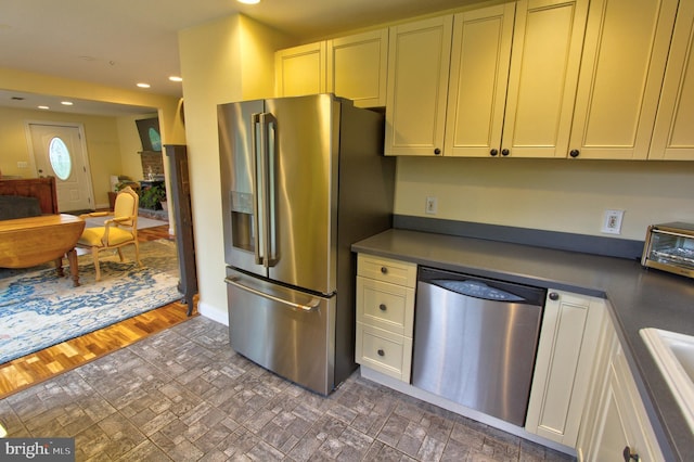 kitchen featuring stainless steel appliances, dark countertops, recessed lighting, a sink, and baseboards
