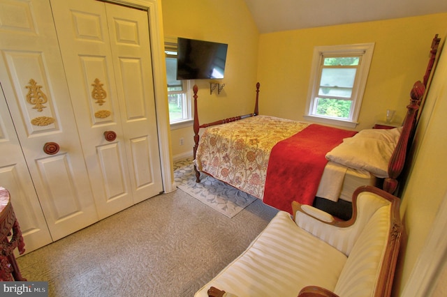 bedroom with multiple windows, lofted ceiling, a closet, carpet flooring, and baseboards