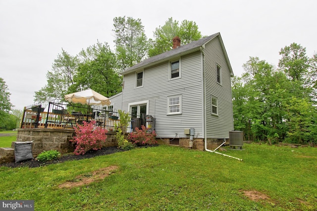 rear view of property featuring a chimney, a lawn, a wooden deck, cooling unit, and french doors