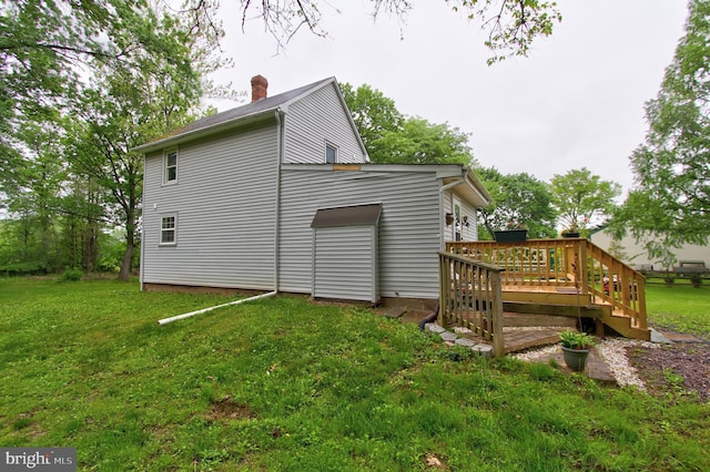 view of side of home featuring a wooden deck, a chimney, and a lawn