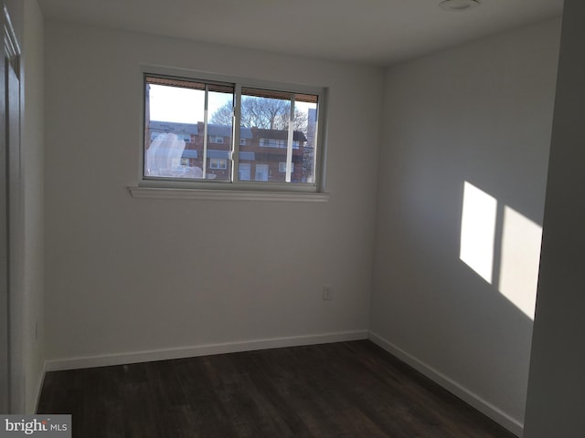 unfurnished room with dark wood-type flooring and baseboards