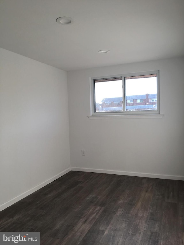 empty room featuring dark wood-style floors, plenty of natural light, baseboards, and recessed lighting