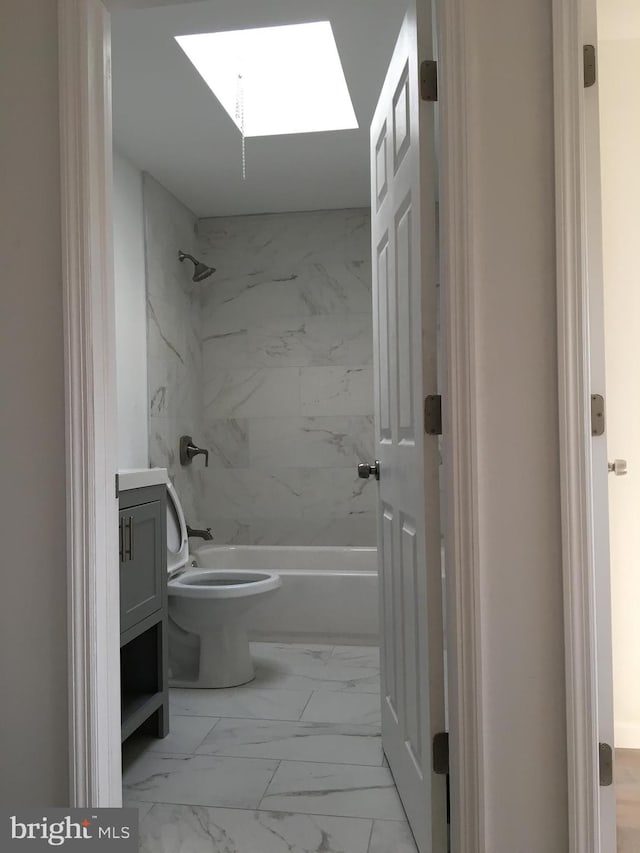 bathroom with marble finish flooring, washtub / shower combination, toilet, a skylight, and vanity