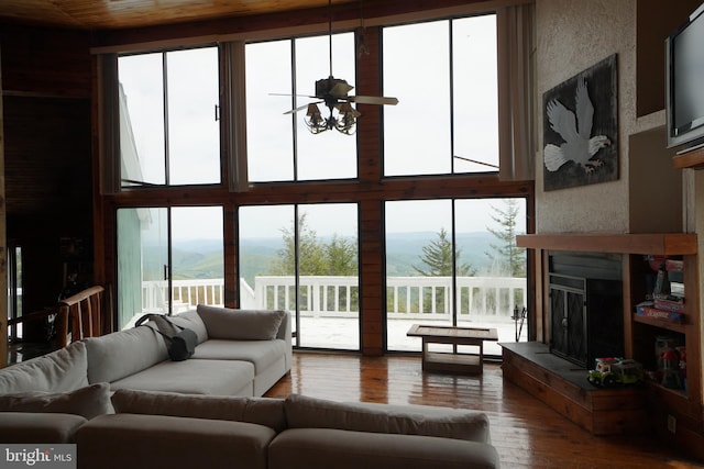 living area with a mountain view, a fireplace, hardwood / wood-style floors, and a towering ceiling