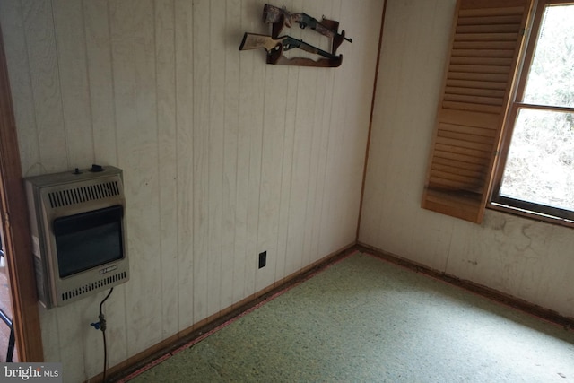 unfurnished dining area featuring heating unit, healthy amount of natural light, wooden walls, and baseboards