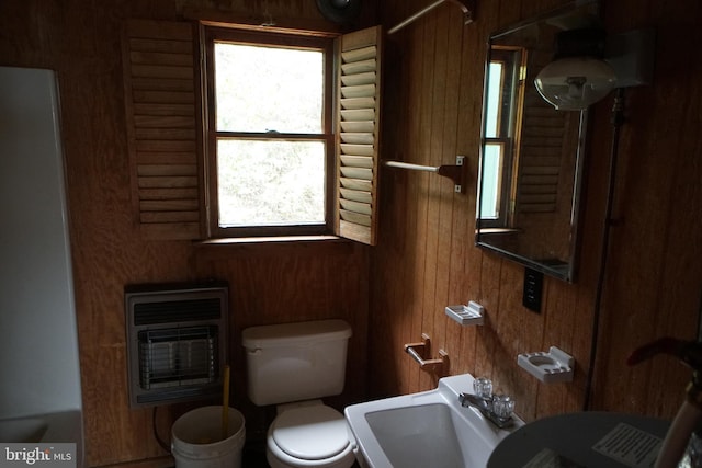 bathroom featuring wooden walls, a sink, toilet, and heating unit