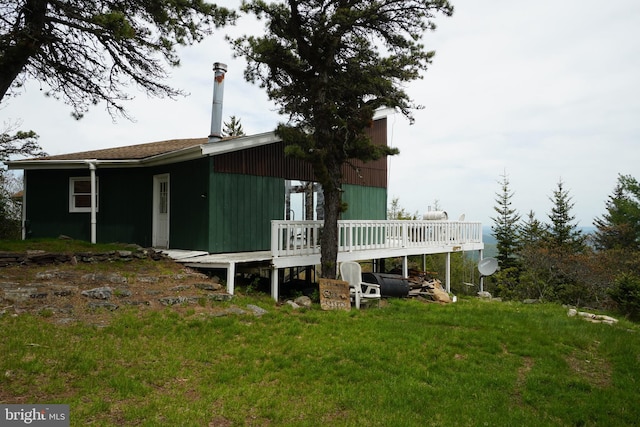 back of property with a deck and a lawn