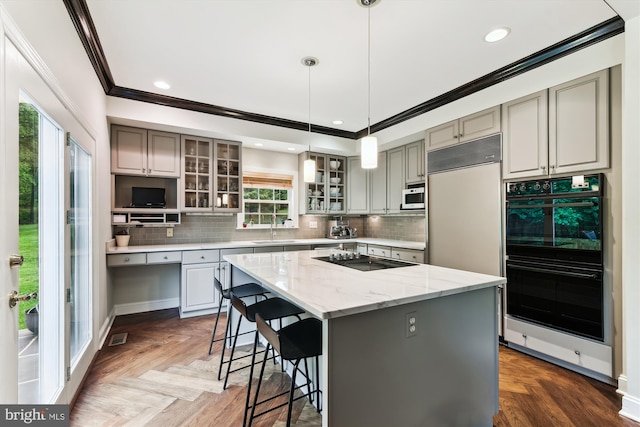 kitchen featuring black appliances, ornamental molding, a sink, decorative backsplash, and a kitchen breakfast bar