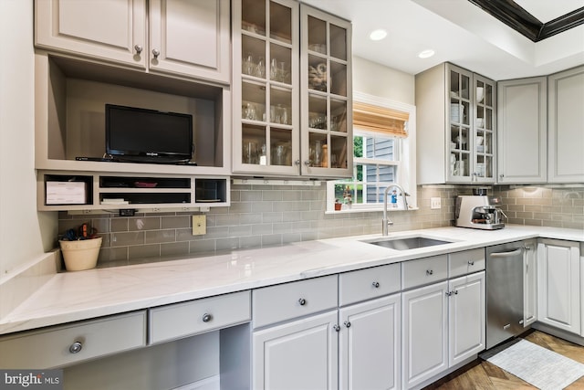 kitchen with a sink, stainless steel dishwasher, tasteful backsplash, light stone counters, and gray cabinets